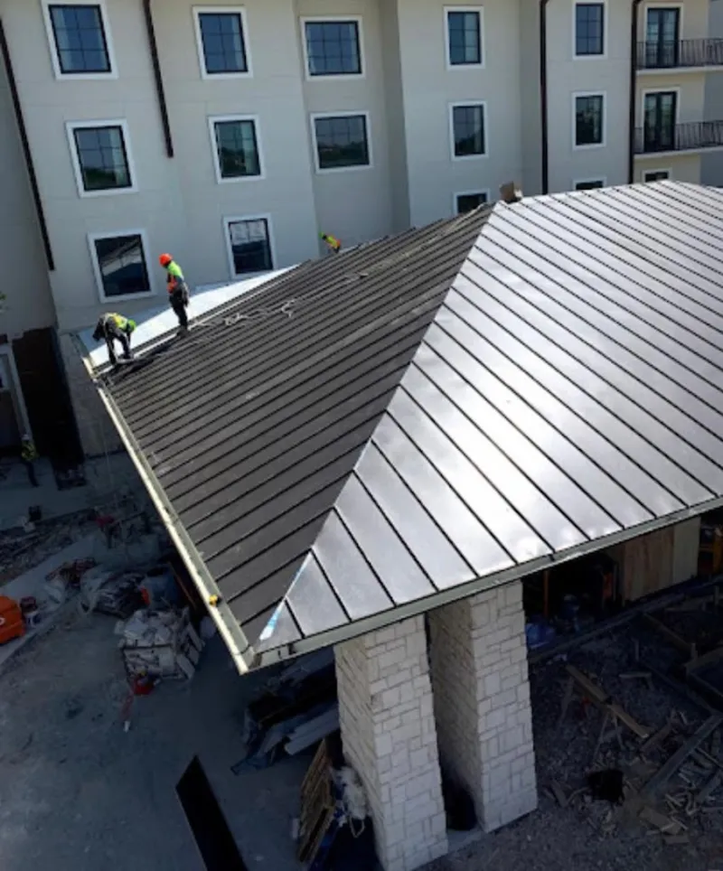 Crew installing standing seam metal roof panels on a commercial project in West Lealman